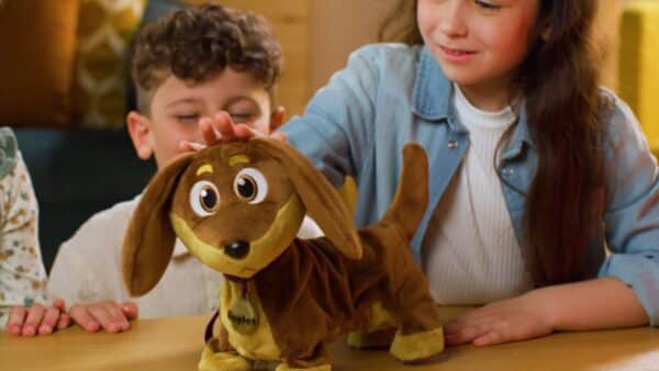 Kinderen spelen met pluchen hond op tafel.