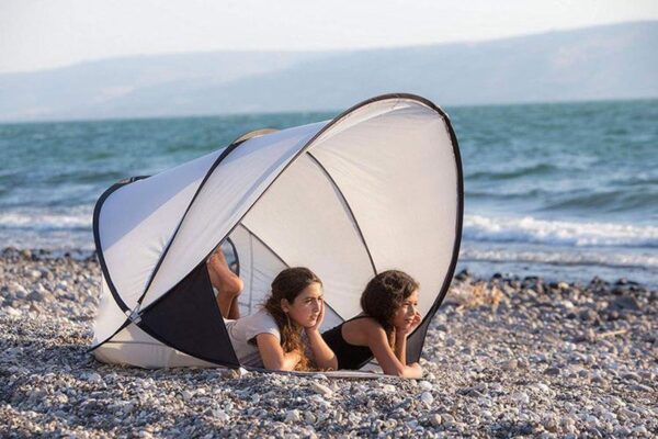 Twee kinderen ontspannen in strandtent op kiezelstrand