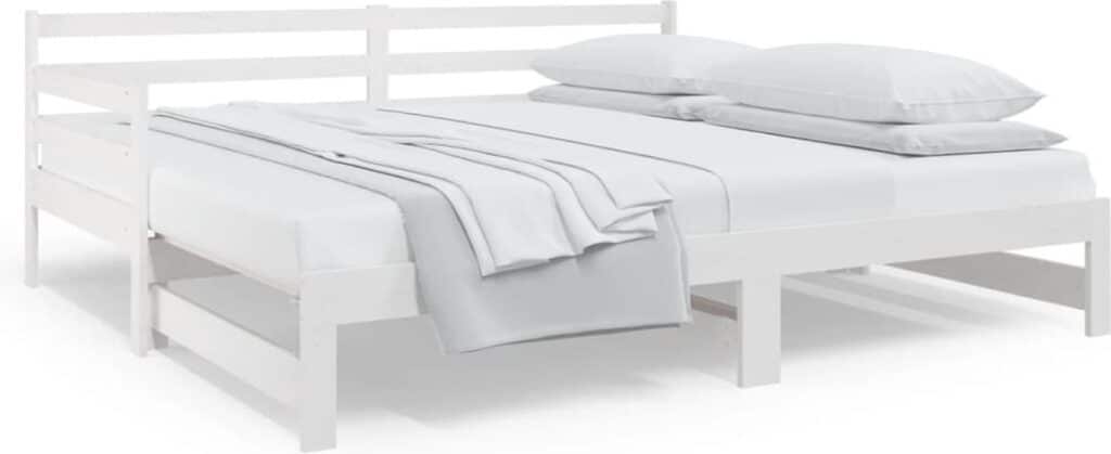 Wit houten bed met beddengoed en kussens.