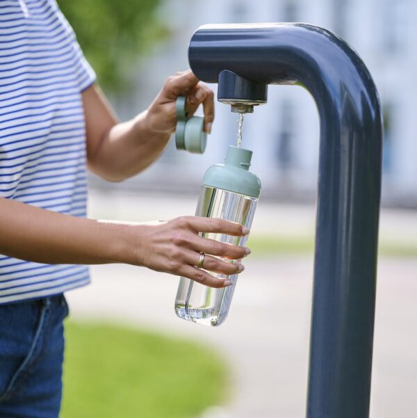 Persoon vult fles met water bij kraan.