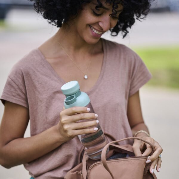 Vrouw pakt fles water uit tas