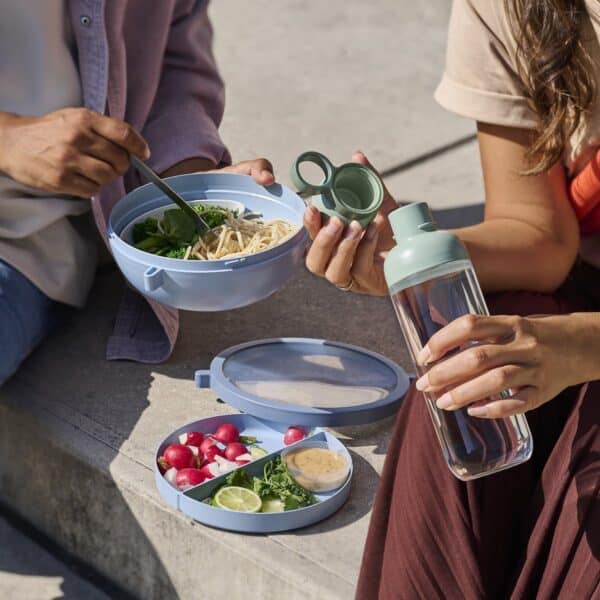 Verslapt lunch met salade en waterfles op de trap.