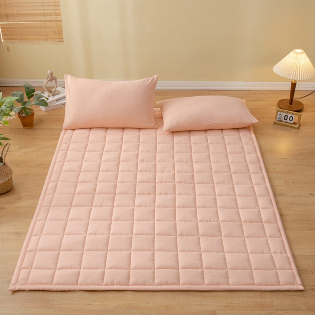 Zachte katoenen matras met roze kussens op vloer.