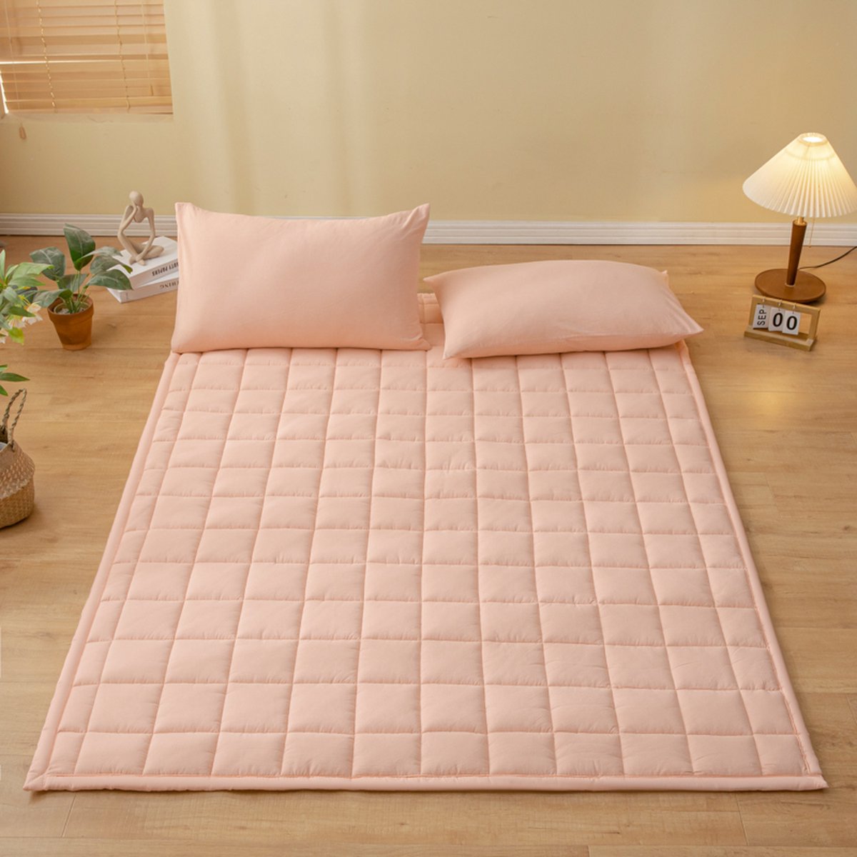 Zachte katoenen matras met roze kussens op vloer.