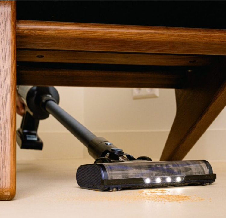 Steelstofzuiger onder tafel met kruimels op vloer